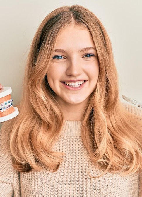teen girl holding teeth with braces and Invisalign 