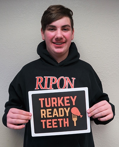 Young man holding sign reading turkey ready teeth after completing orthodontic treatment