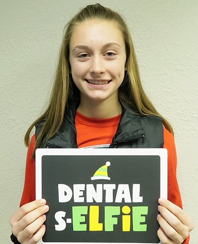 Young woman holding sign that says dental selfie after finishing orthodontic treatment