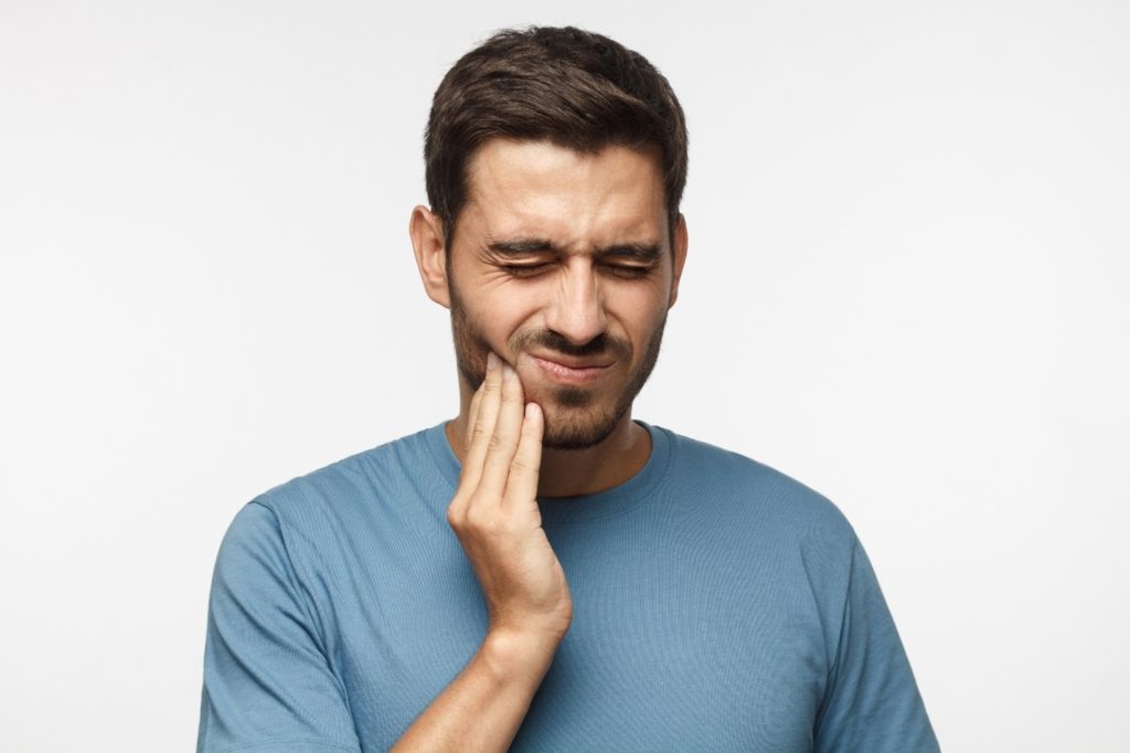Closeup of man in blue shirt with jaw pain